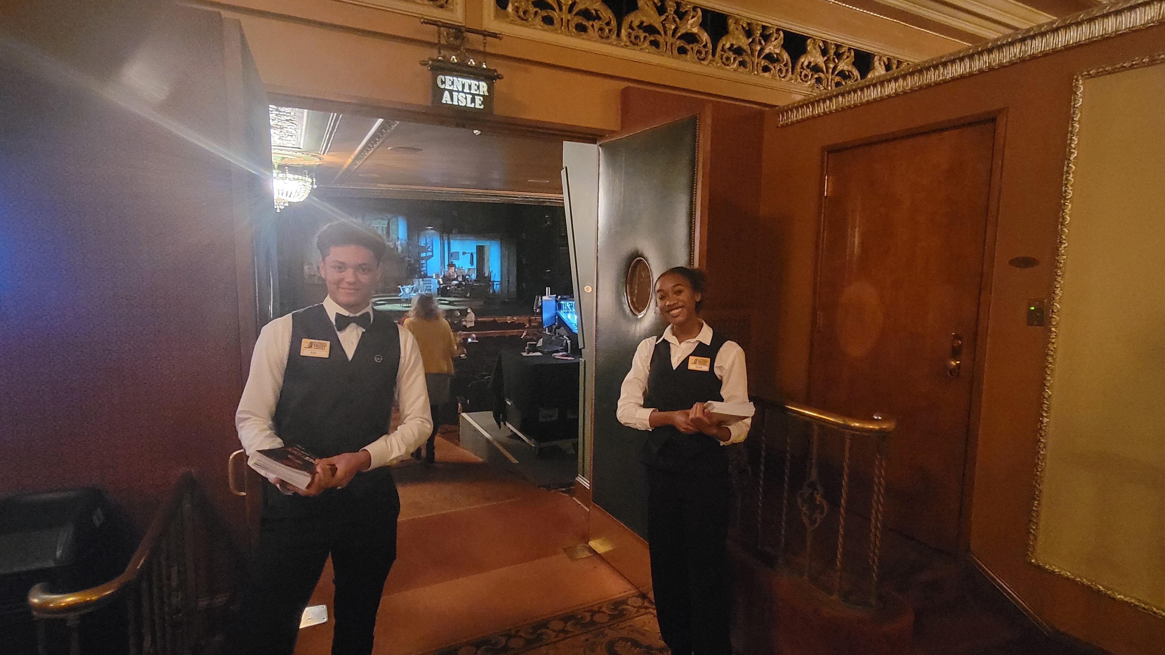 two volunteers holding programs at the entrance to the Benedum auditorium
