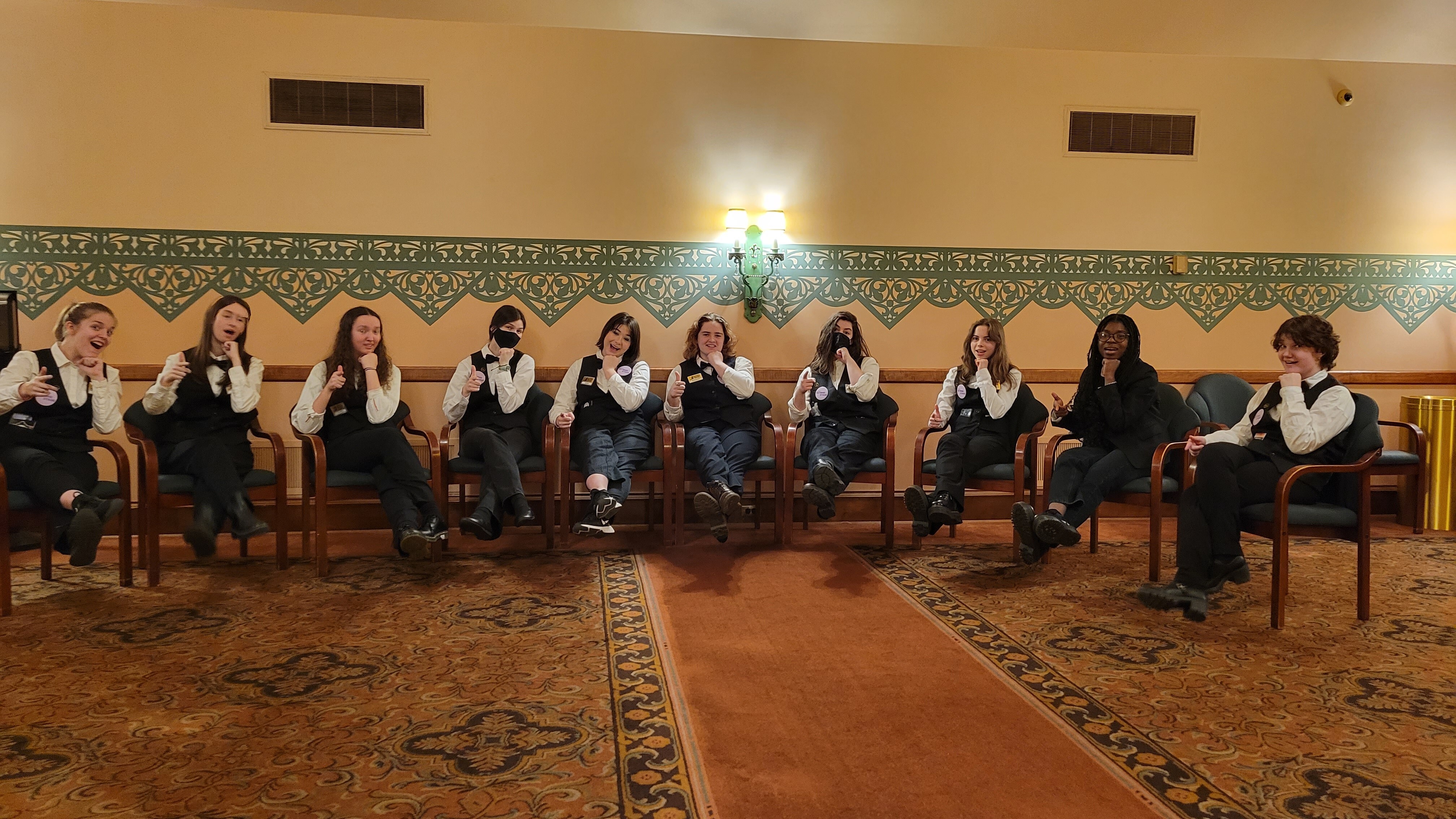 a group of volunteers in uniform sitting in chairs in the Bendum lobby