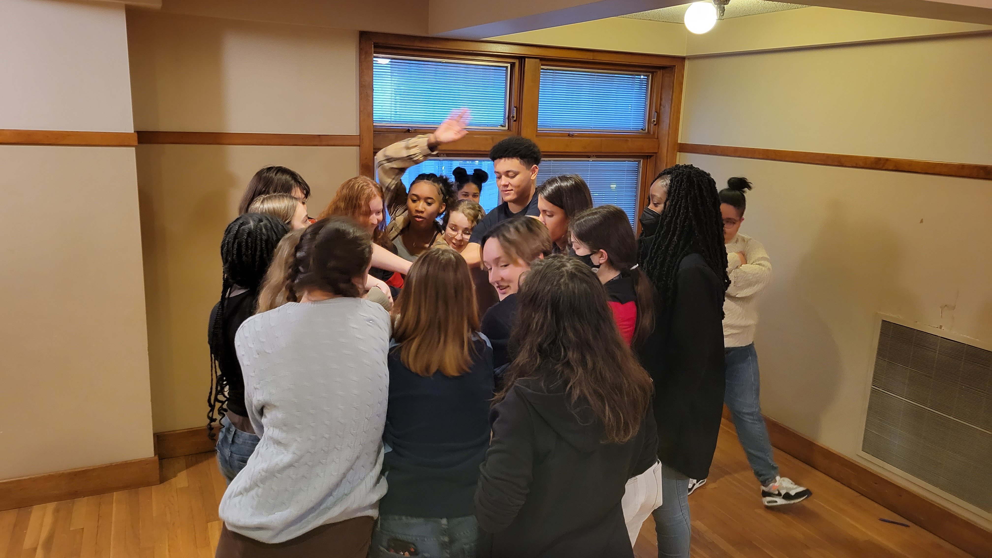 a group of students in a huddle with hands in the center