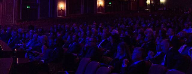 An audience sits in a darkened Benedum auditorium.