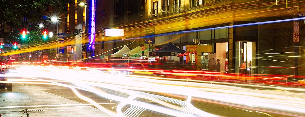 a photo of Liberty Avenue at night during a gallery crawl with light trails from passing cars and buses