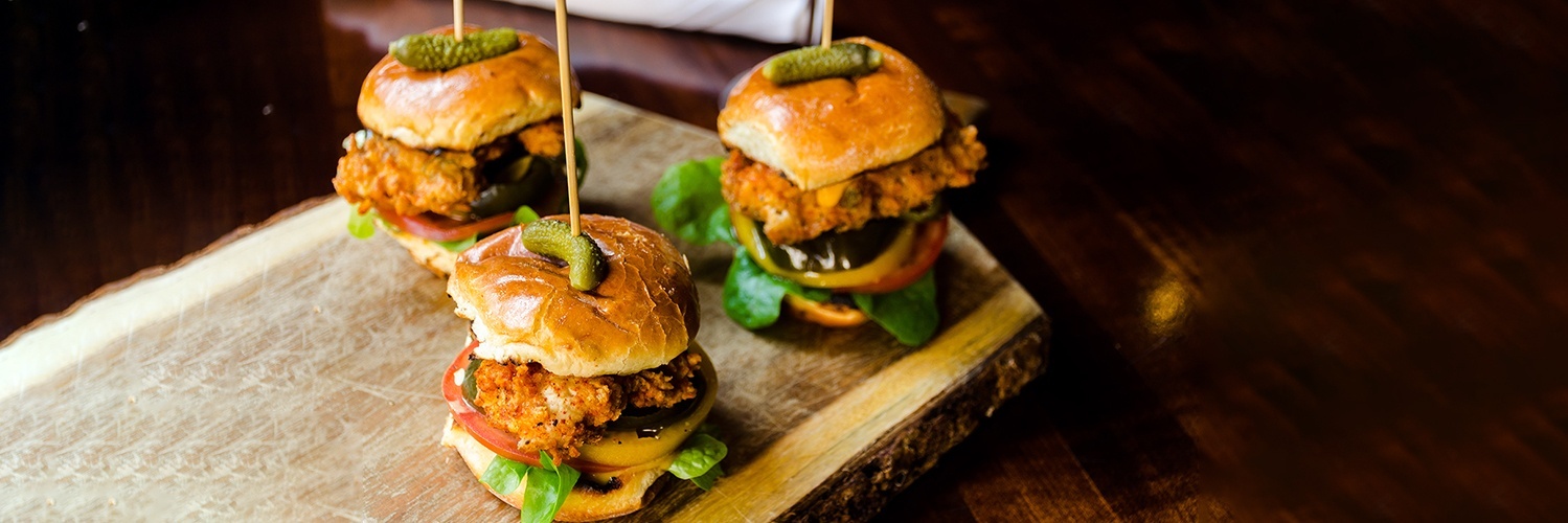three chicken sliders and a bright purple cocktail in a martini glass