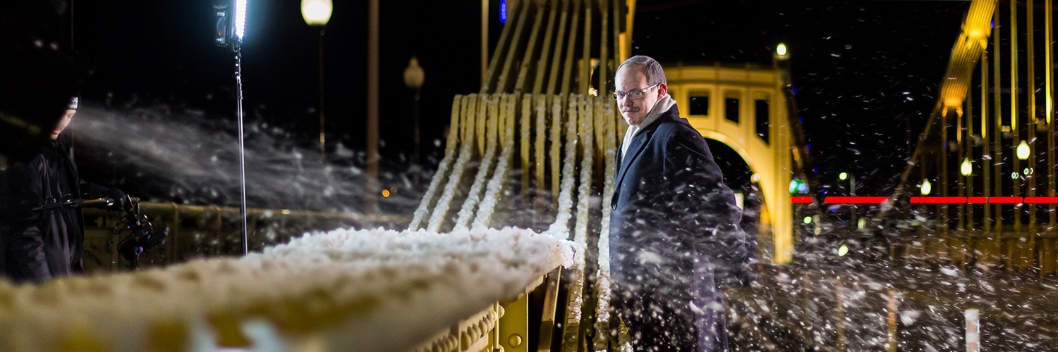 actor portraying kevin mcmahon standing on a bridge at night