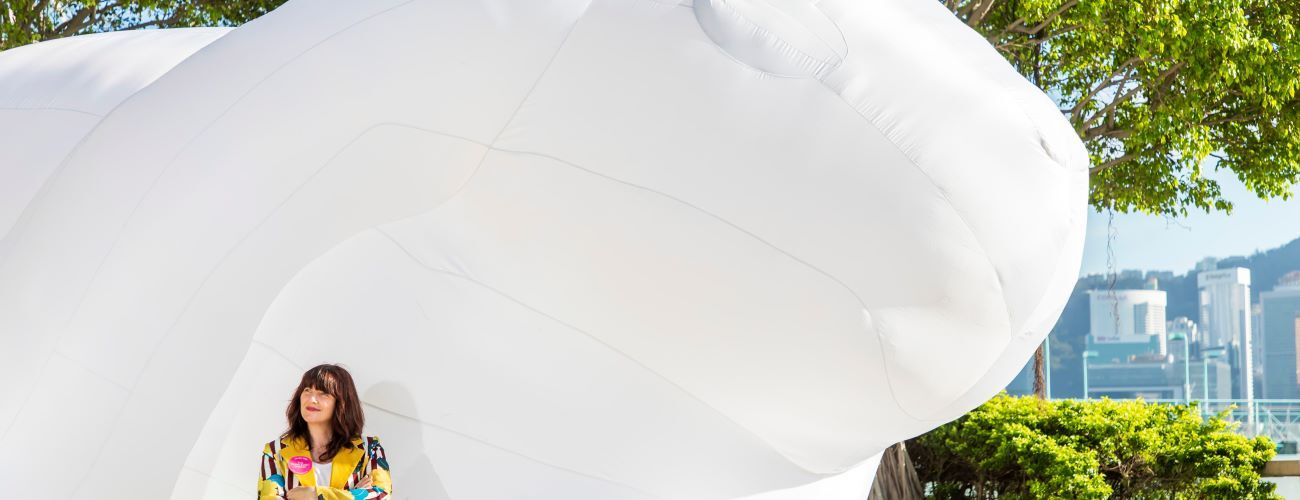 Artist Amanda Paper standing in front of her work, Intrude, a very large white bunny