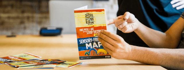 A man points at a map with the Three Rivers Arts Festival logo that says Sensory-Friendly Map.