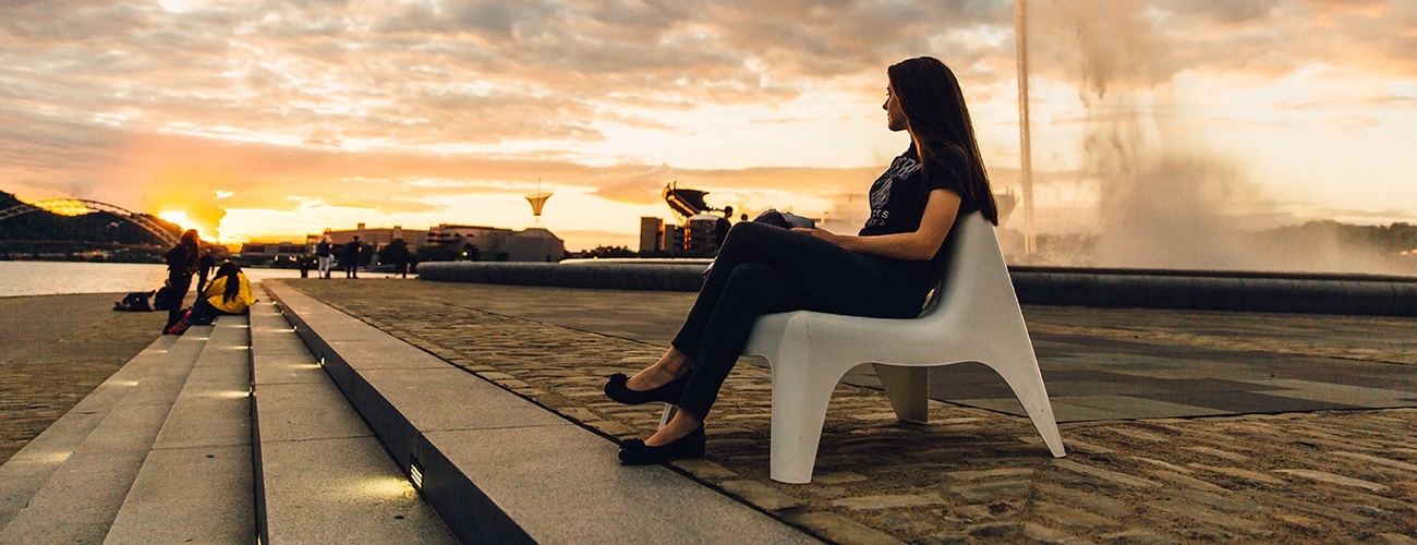a woman sits at point state park at sunset