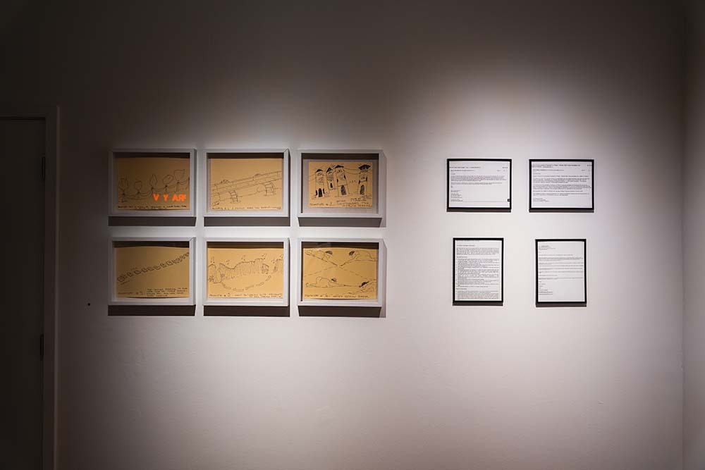 Six drawings on parchment hung next to four printed out emails