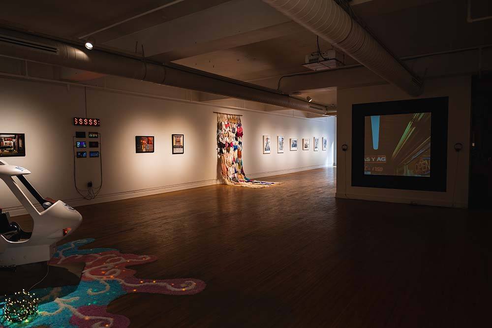 A wide view of the rear portion of the exhibition, with a projection on the right, a fabric piece in the center, and a child's ride converted to look like an ICE helicopter on the left