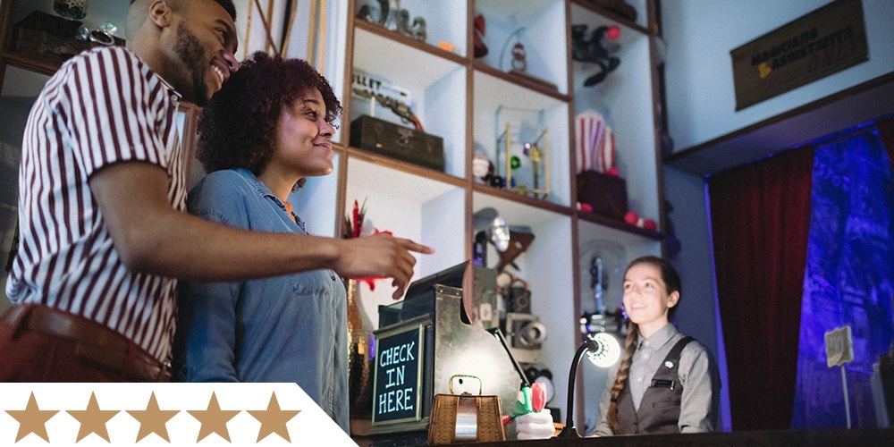 two patrons entering the lobby of liberty magic, smiling and pointing at something off frame