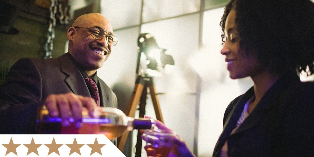 one visitor smiles while pouring wine for another patron in front of liberty magic's byob station