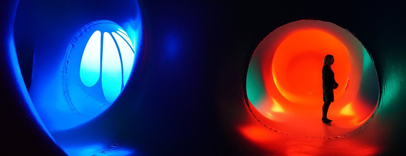 the interior of a large, blue and red inflatable space. the silhouette of a woman stands in the distance.