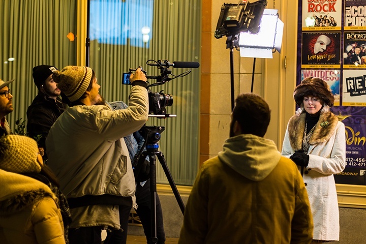 camera operator adjusts settings for a shot in front of the benedum center