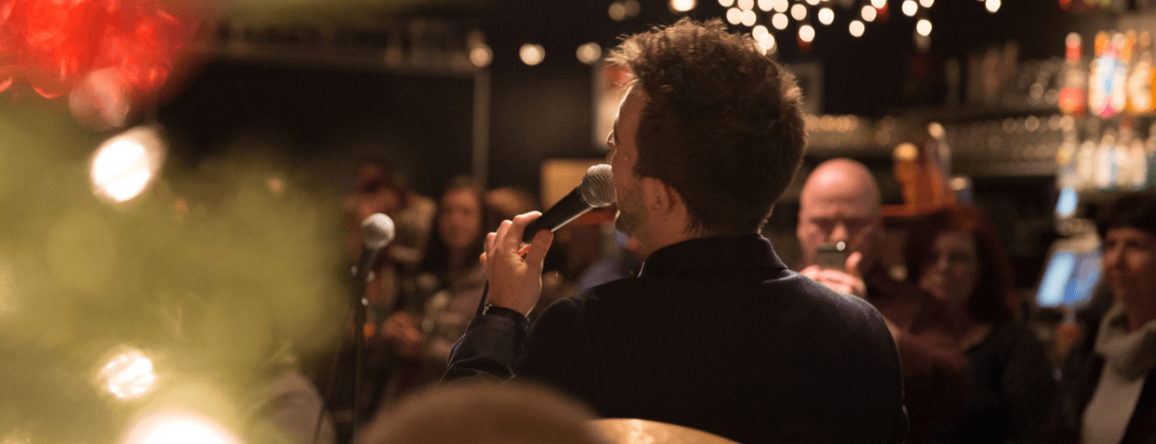 view of man singing from behind with people gathered in front of him