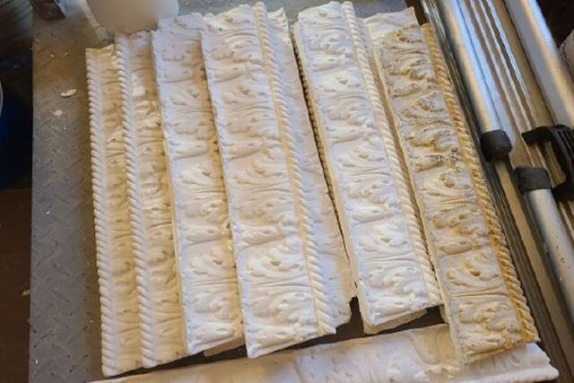 A number of white, ornate pieces of plaster molding sits ready to be applied.