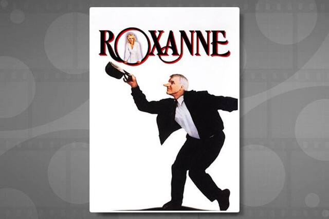 Movie poster with the title Roxanne. A man in a white shirt and black suit with an unnaturally long nose holds up black hat in one hand.
