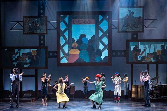 Black dancers in early 20th century costumes dance on stage with five murals behind them.