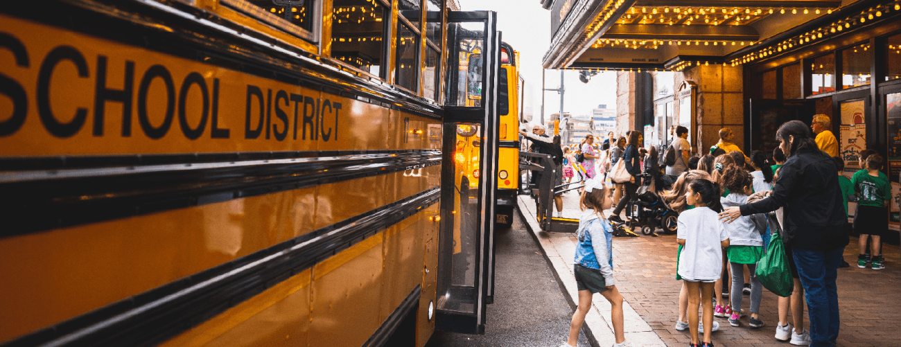 students getting off a yellow school bus in the Cultural District