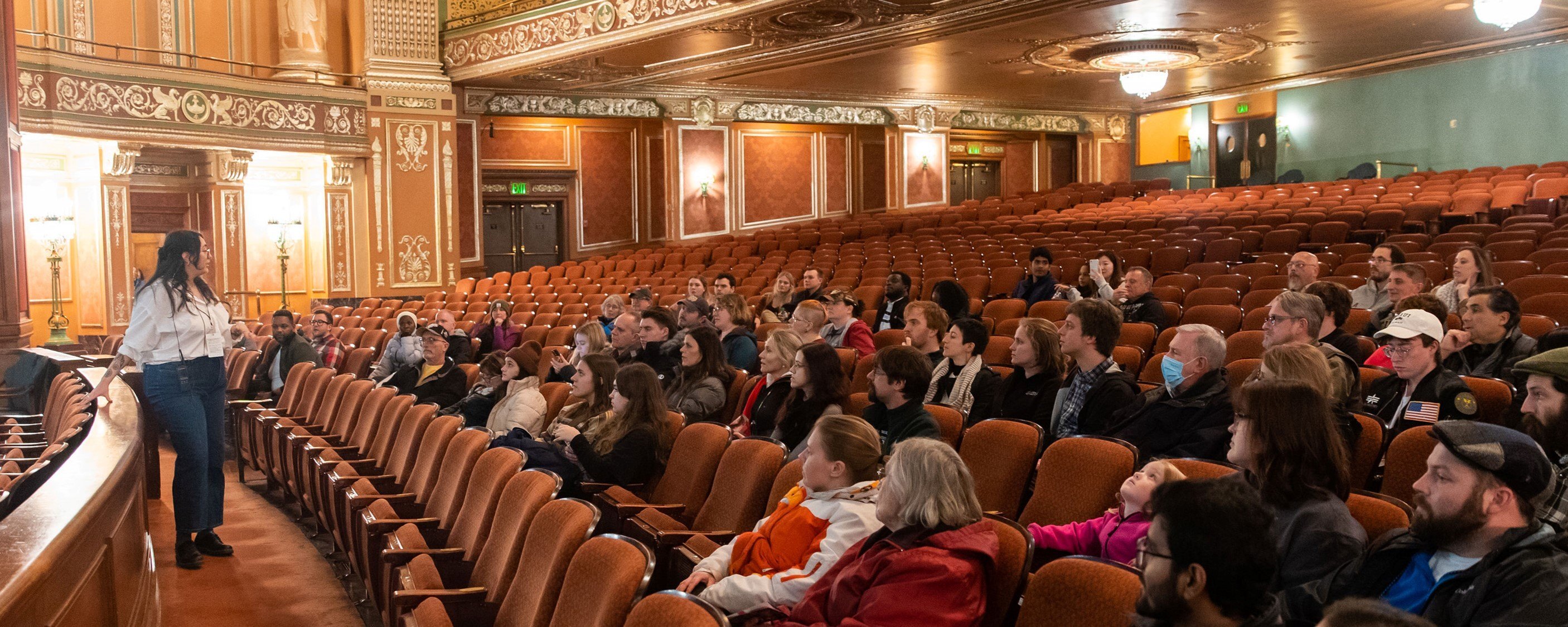 a group of people sit in Benedum Center seats, facing a tour guide