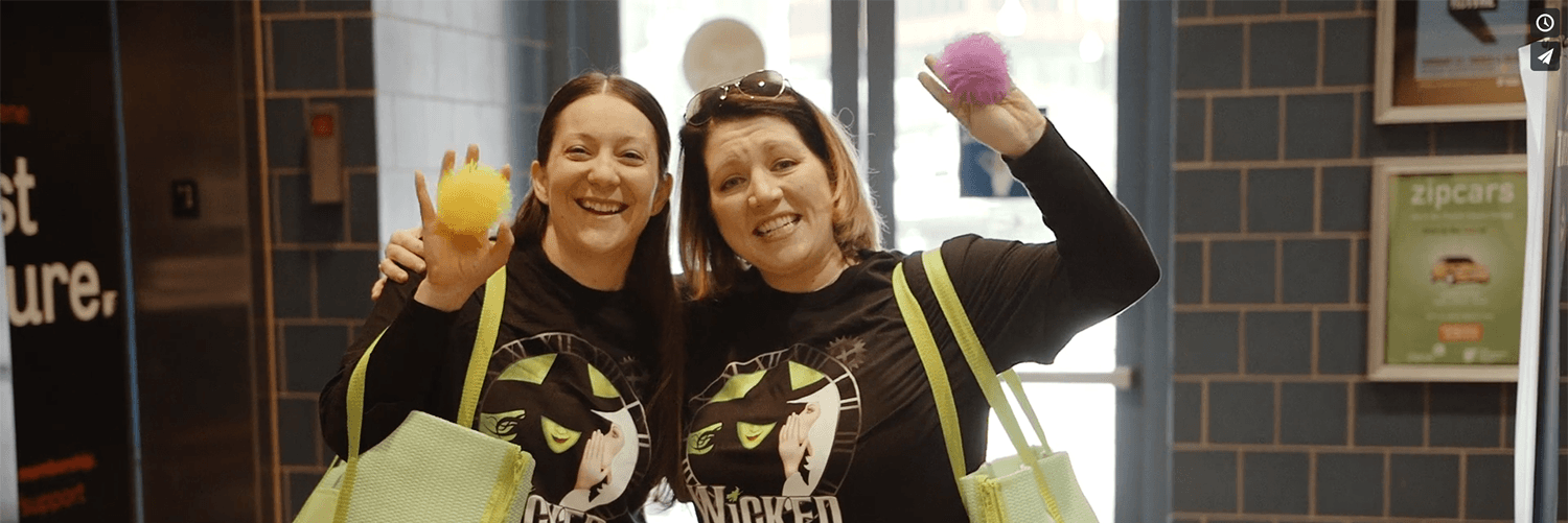 two volunteers in Wicked shirts holding fidgets