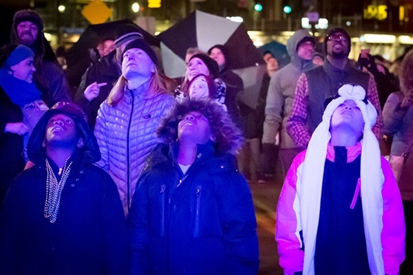 three kids bundled in coats stand to watch fireworks at Highmark First Night Pittsburgh on New Year's Eve
